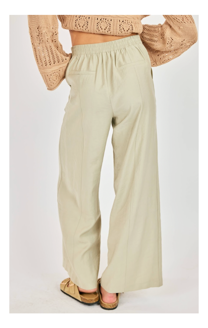 Beige wide-leg pants worn with a beige crochet top on a white background