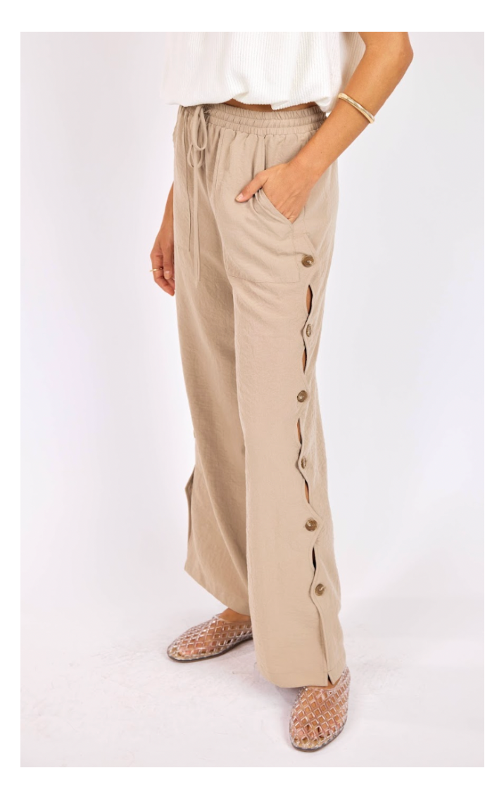 Beige pants with button details on a white background