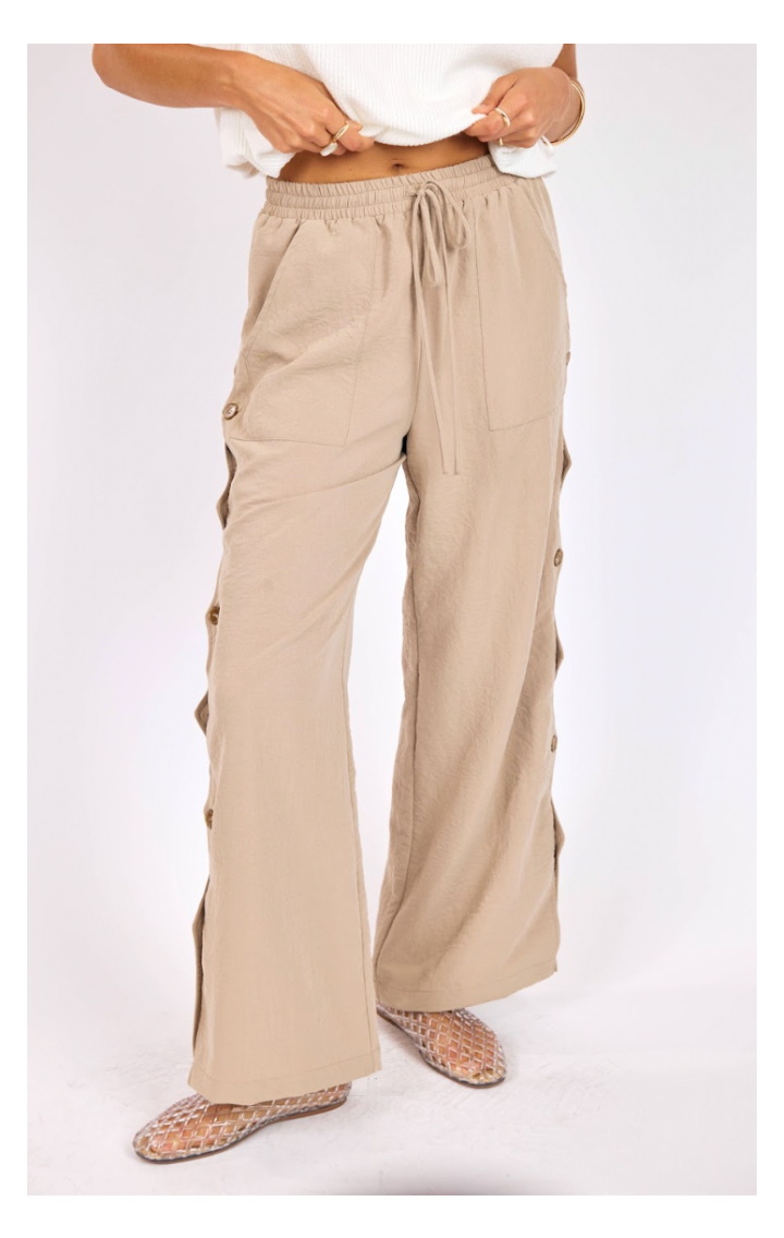 Beige pants with button details on a white background