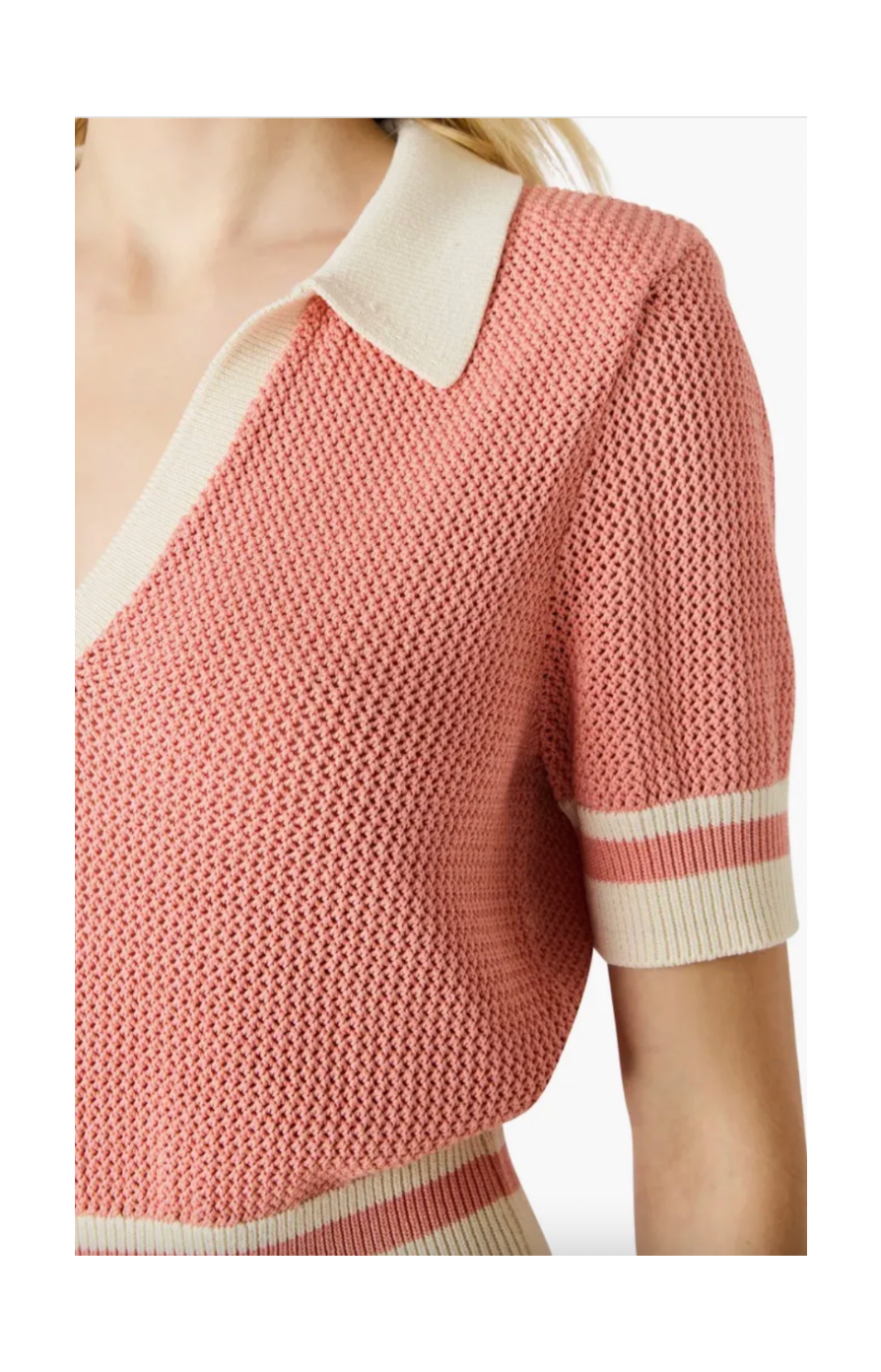 Pink knitted sweater with white collar and sleeves on a blurred background
