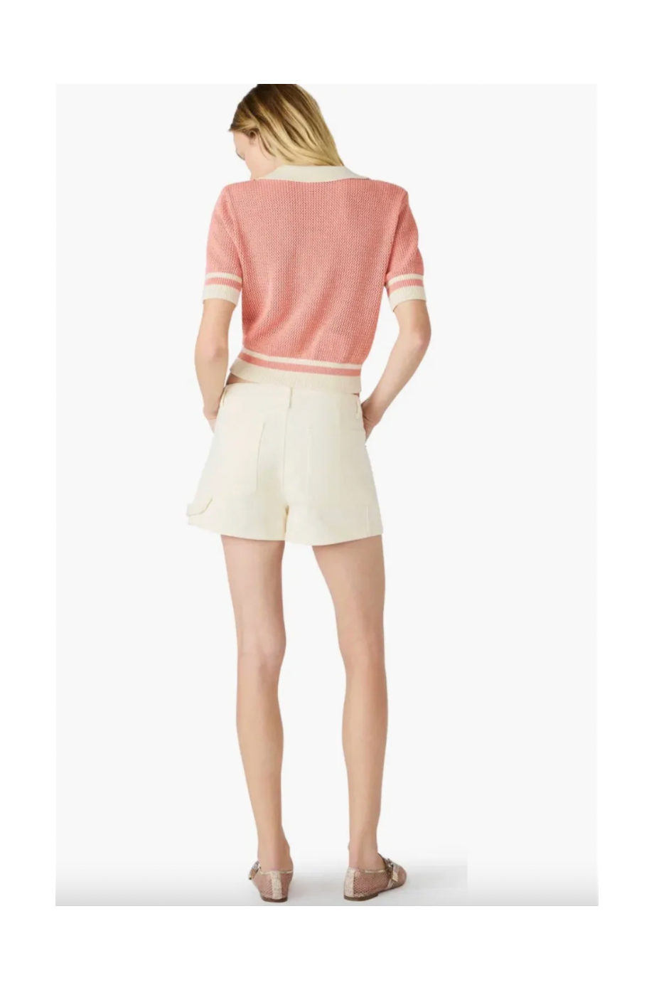 Person wearing a pink sweater and white shorts on a white background