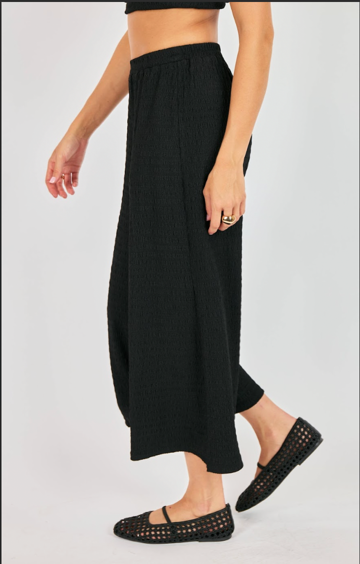 Person wearing black wide-leg pants on a white background