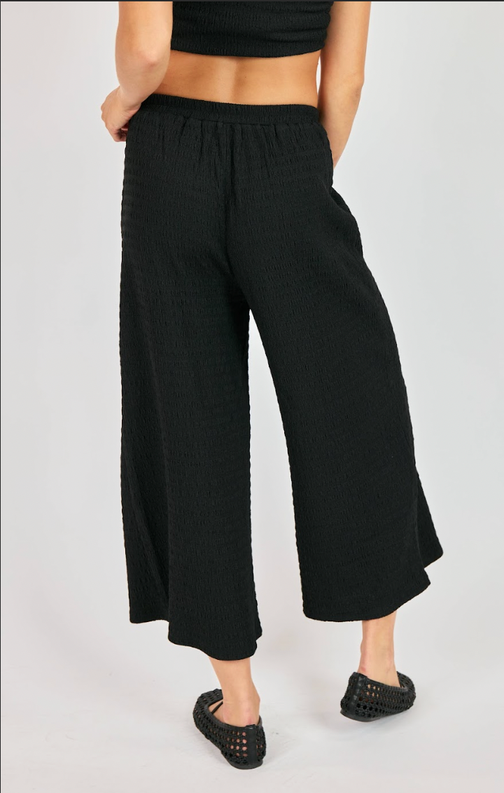 Person wearing black wide-leg pants on a white background
