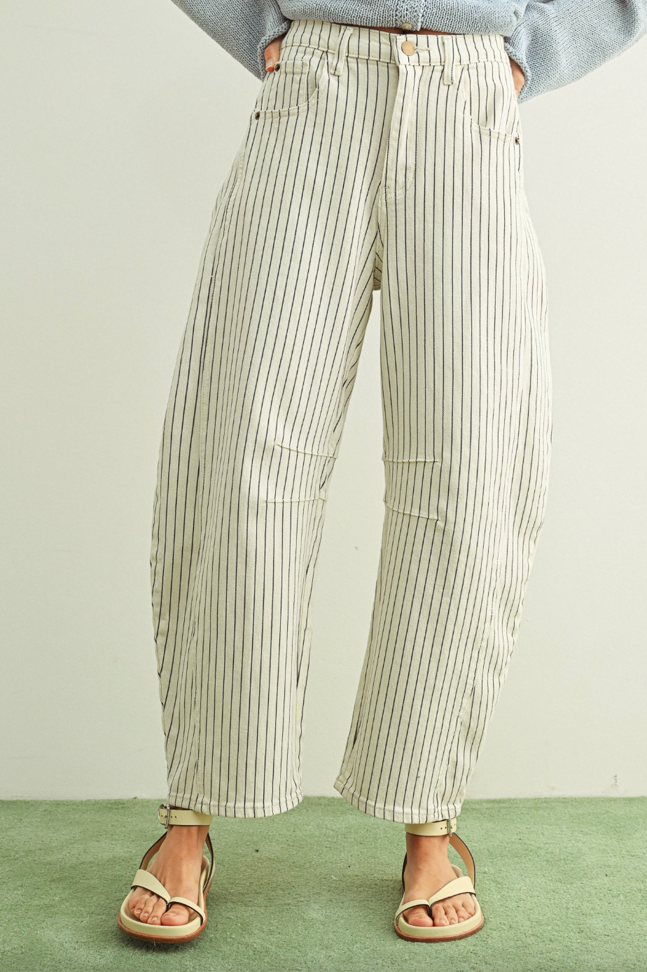 Person wearing striped pants and sandals on a plain background