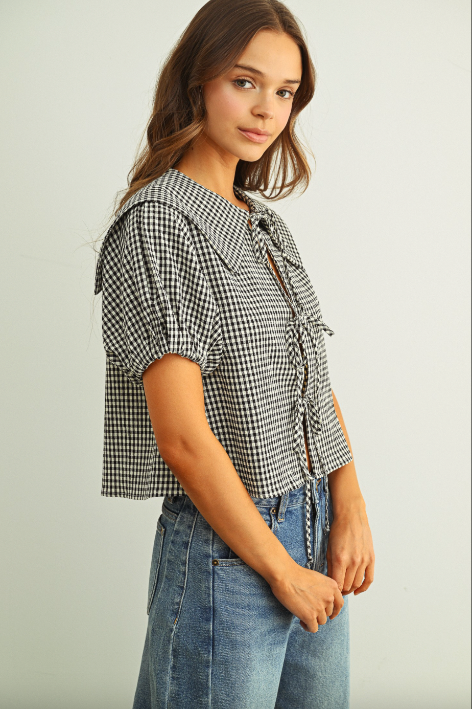 Woman wearing a checkered blouse and jeans on a plain background