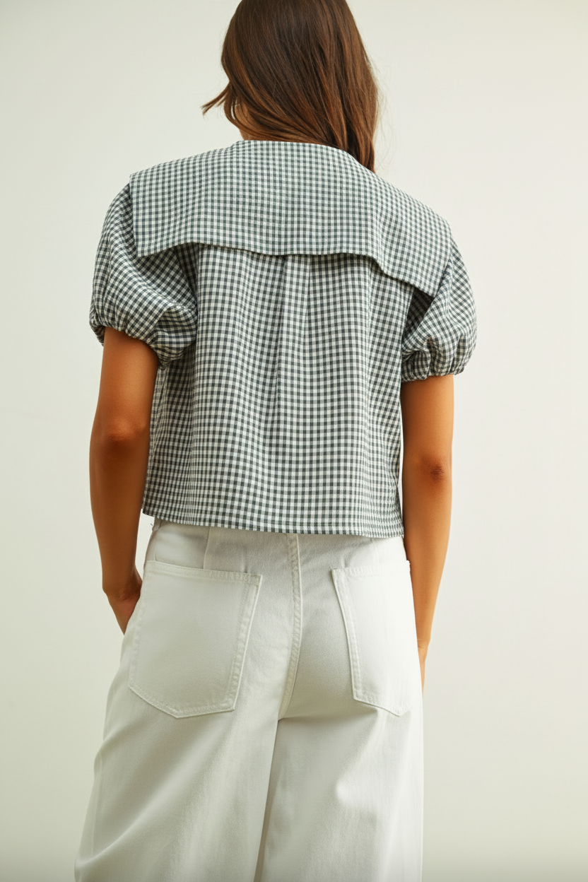 Person wearing a checkered shirt and light pants on a plain background