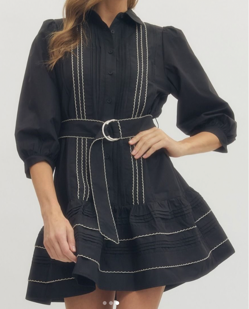 Woman wearing a black dress with white stitching on a white background