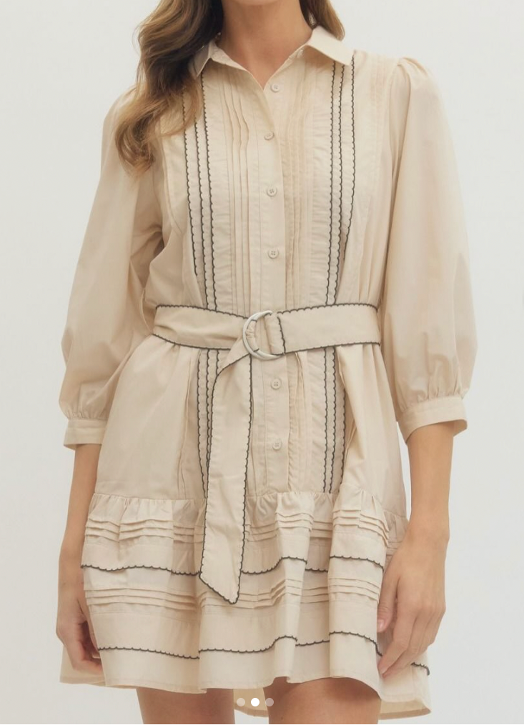 Woman wearing a beige dress with black stripes on a white background