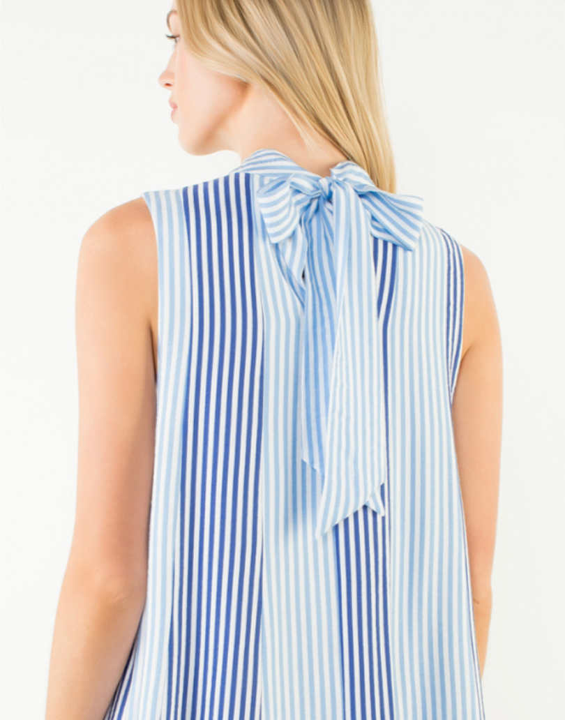Woman wearing a blue and white striped sleeveless top with a bow detail on a white background