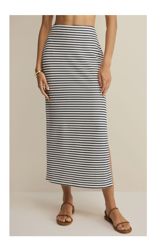 Person wearing a black and white striped skirt on a beige background