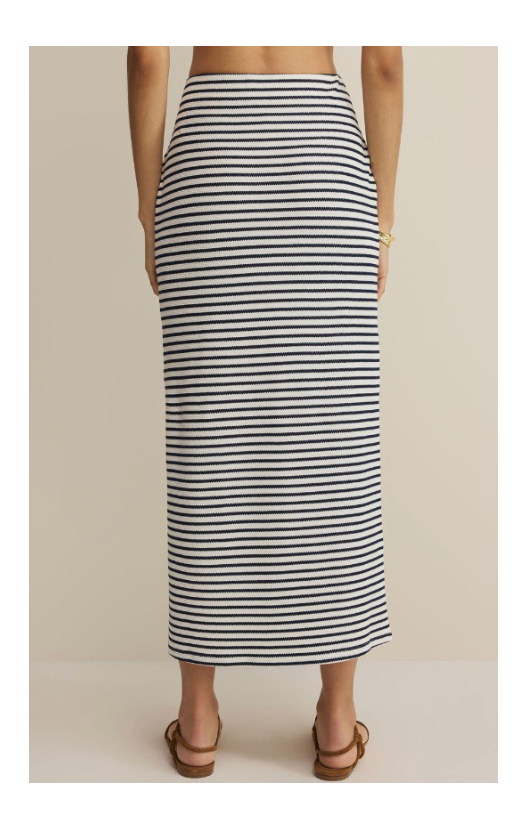 Person wearing a black and white striped skirt on a beige background