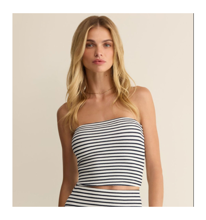 Woman wearing a black and white striped strapless top against a beige background