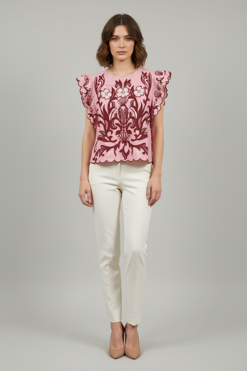 Woman wearing a pink floral blouse and white pants on a gray background