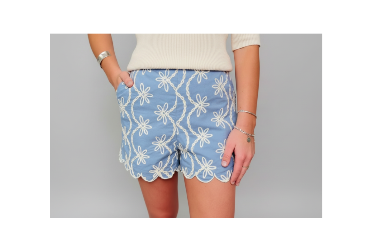 Blue shorts with white floral pattern worn by a person on a gray background