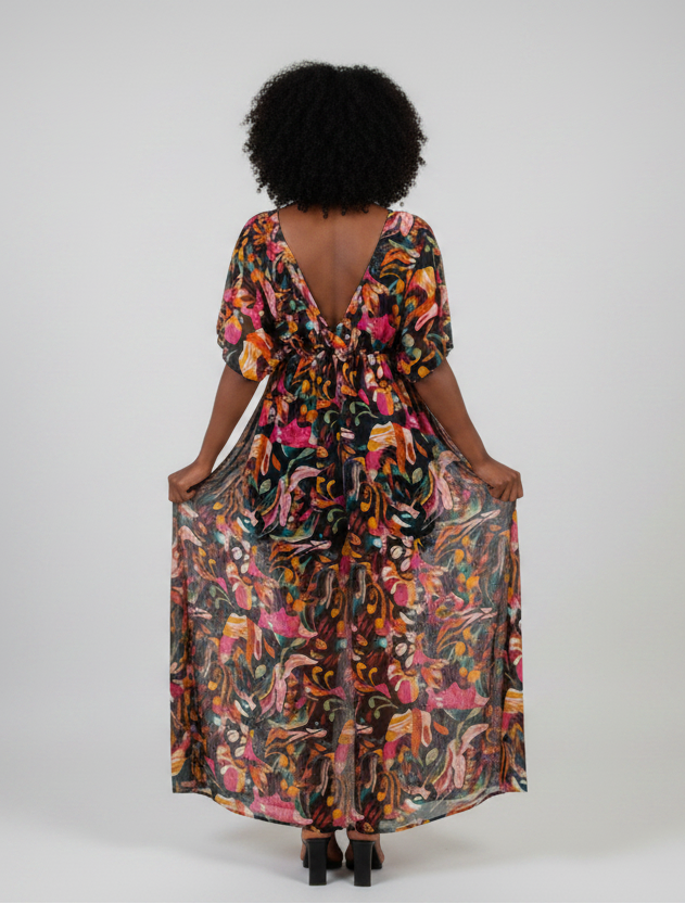 Woman wearing a colorful floral dress against a white wall.