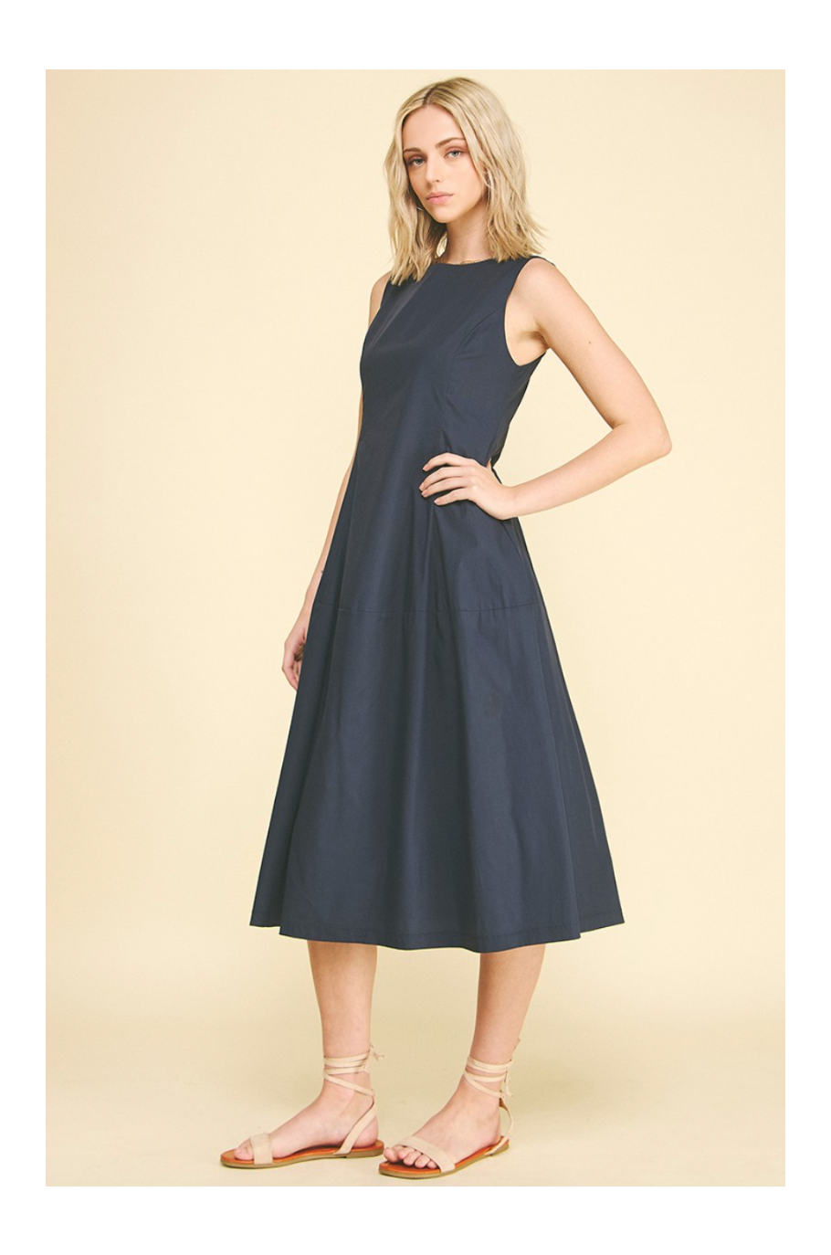 Woman wearing a navy sleeveless dress on a beige background