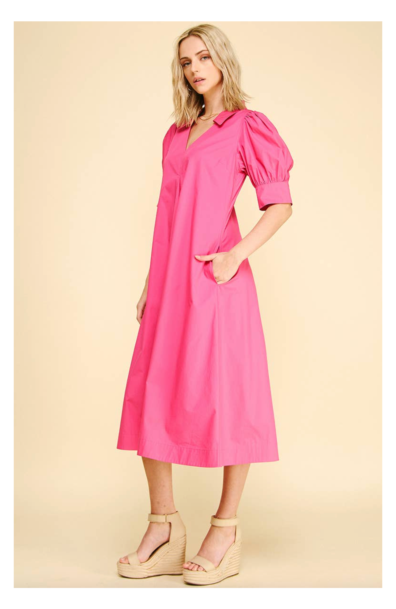 Woman wearing a pink dress with puff sleeves on a beige background