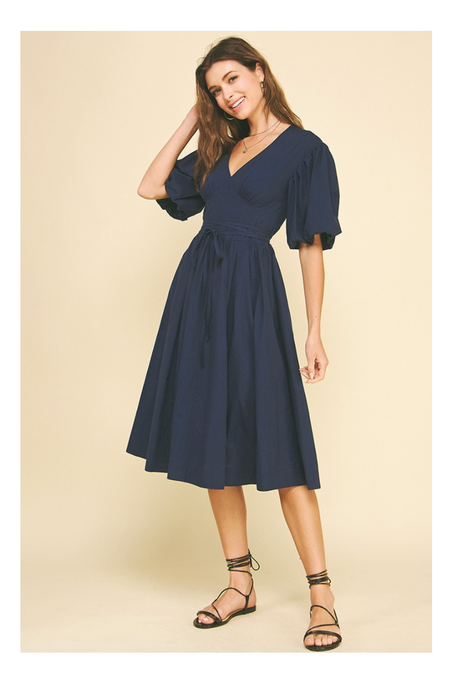 Woman wearing a navy blue dress on a beige background