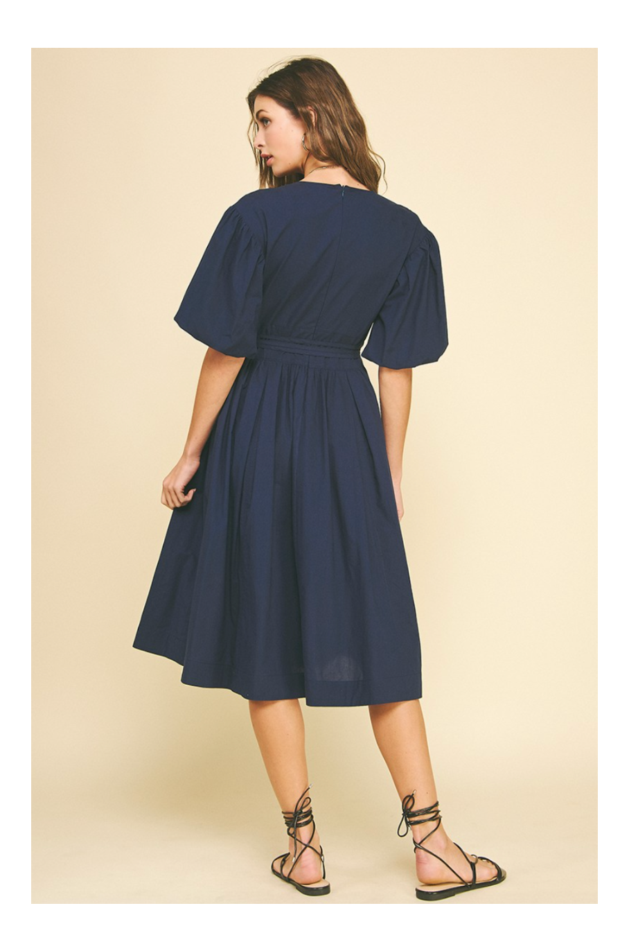 Woman wearing a navy blue dress on a beige background