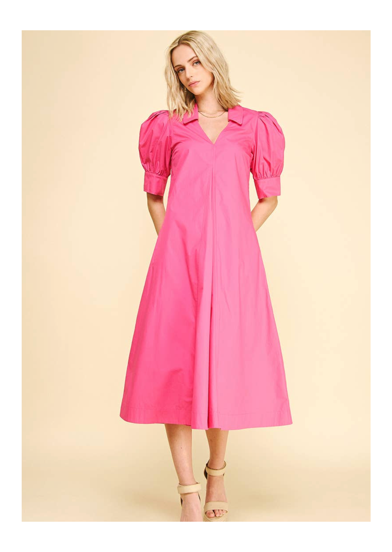 Woman wearing a pink dress with puff sleeves on a beige background