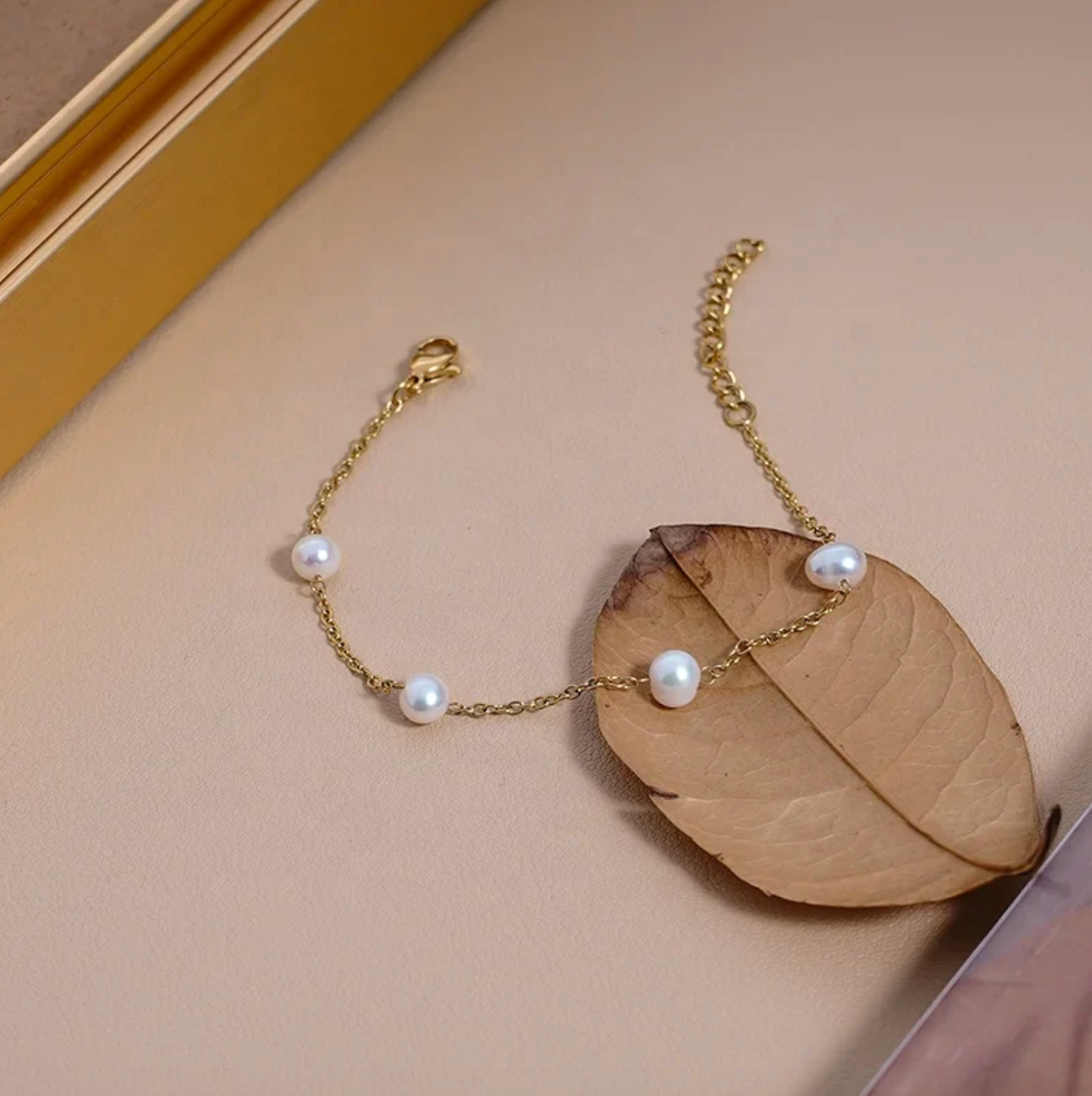 Gold bracelet with pearls on a beige background