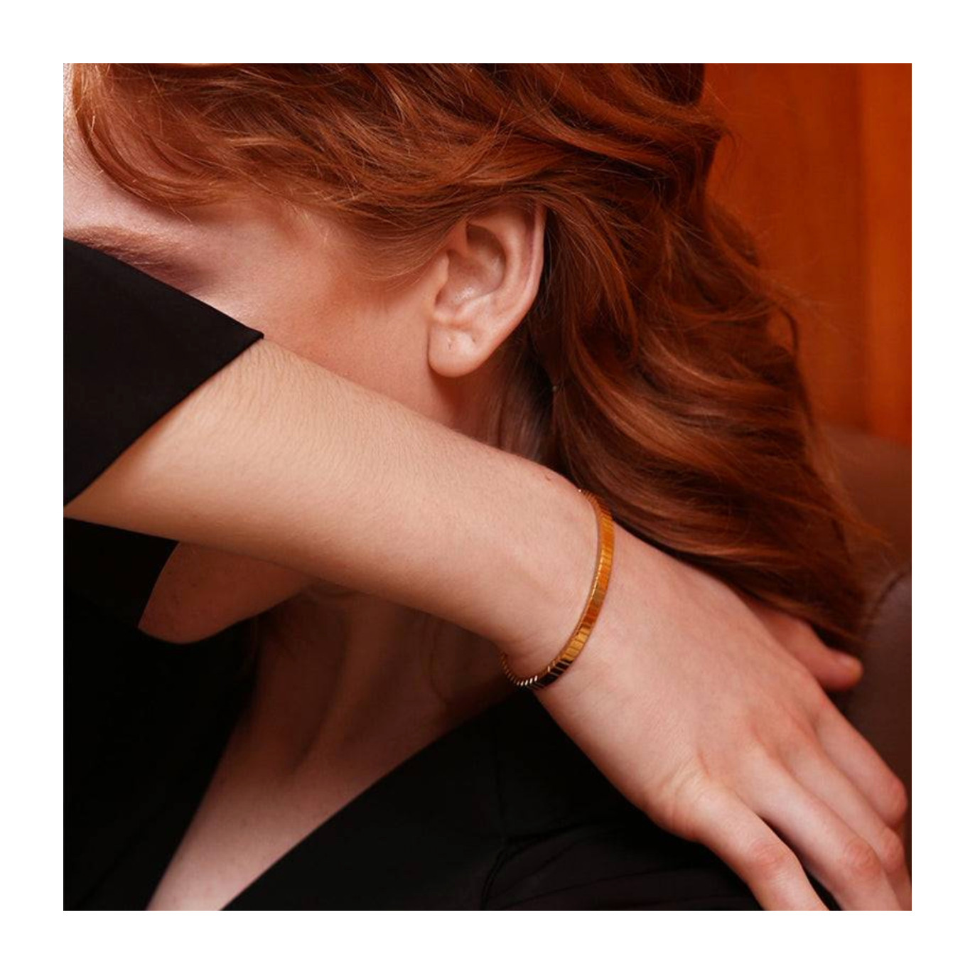 Close-up of a person wearing a gold bracelet with a blurred background
