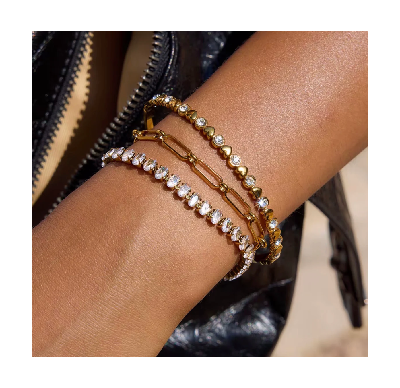 Gold and rose gold bracelet with clear stones on a wrist against a blurred background