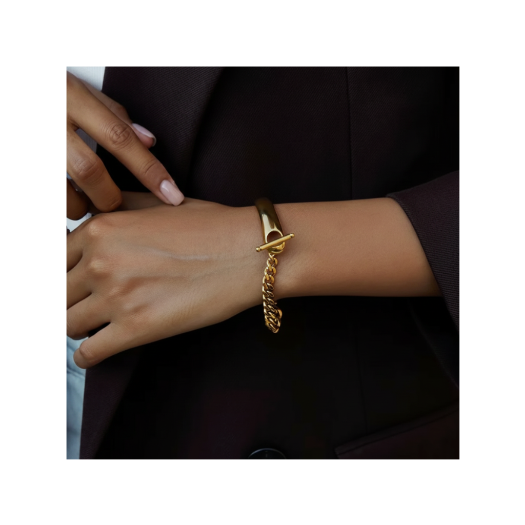 Gold chain bracelet on a wrist with a dark background
