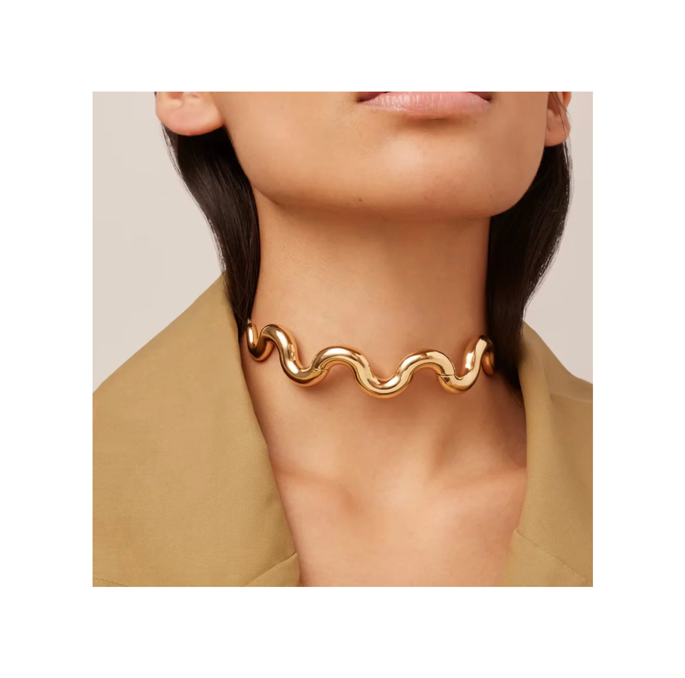 Gold necklace worn by a person with a neutral background