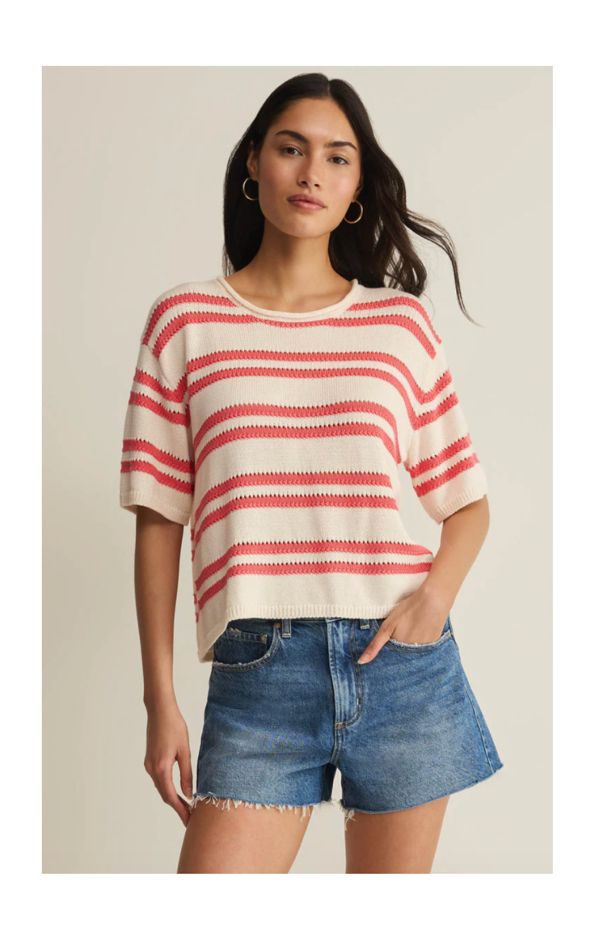 Woman wearing a red and white striped sweater and denim shorts on a beige background