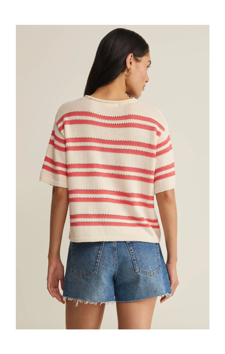 Woman wearing a red and white striped sweater and denim shorts on a beige background