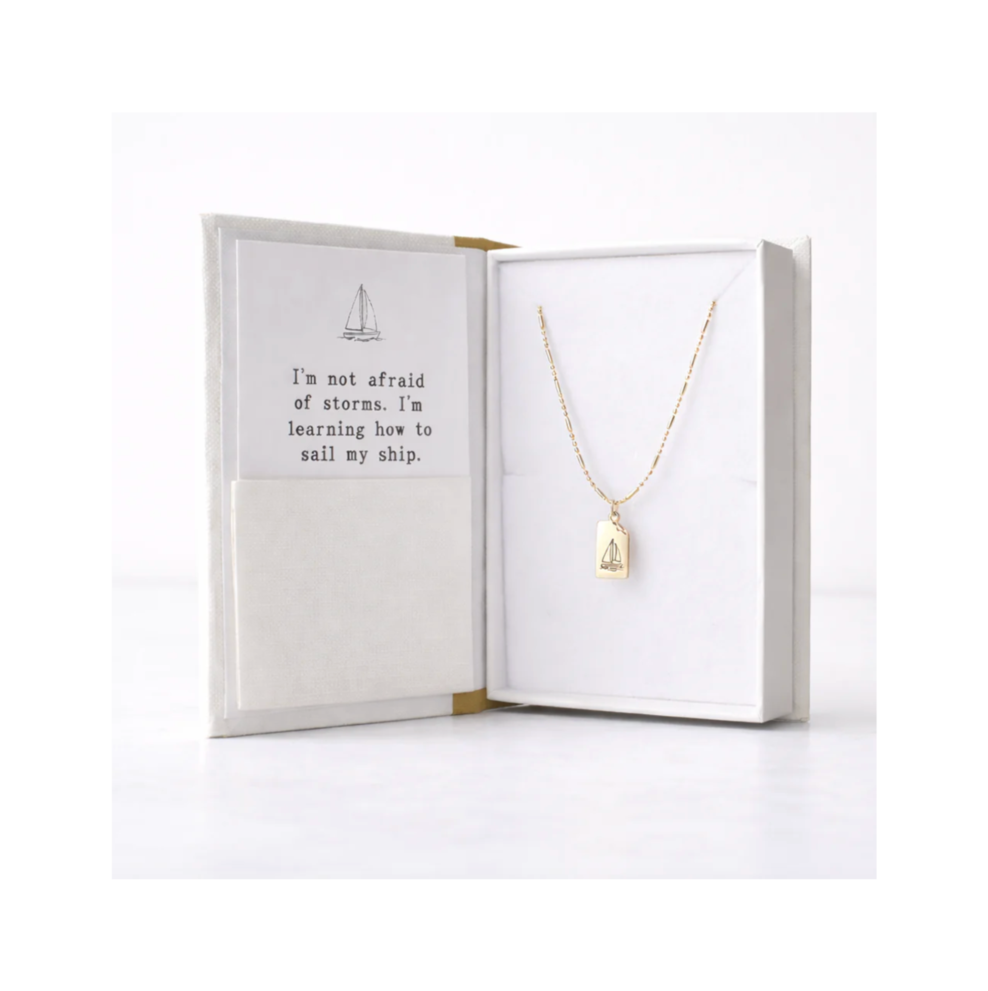 Gold necklace with a pendant in an open jewelry box on a white background