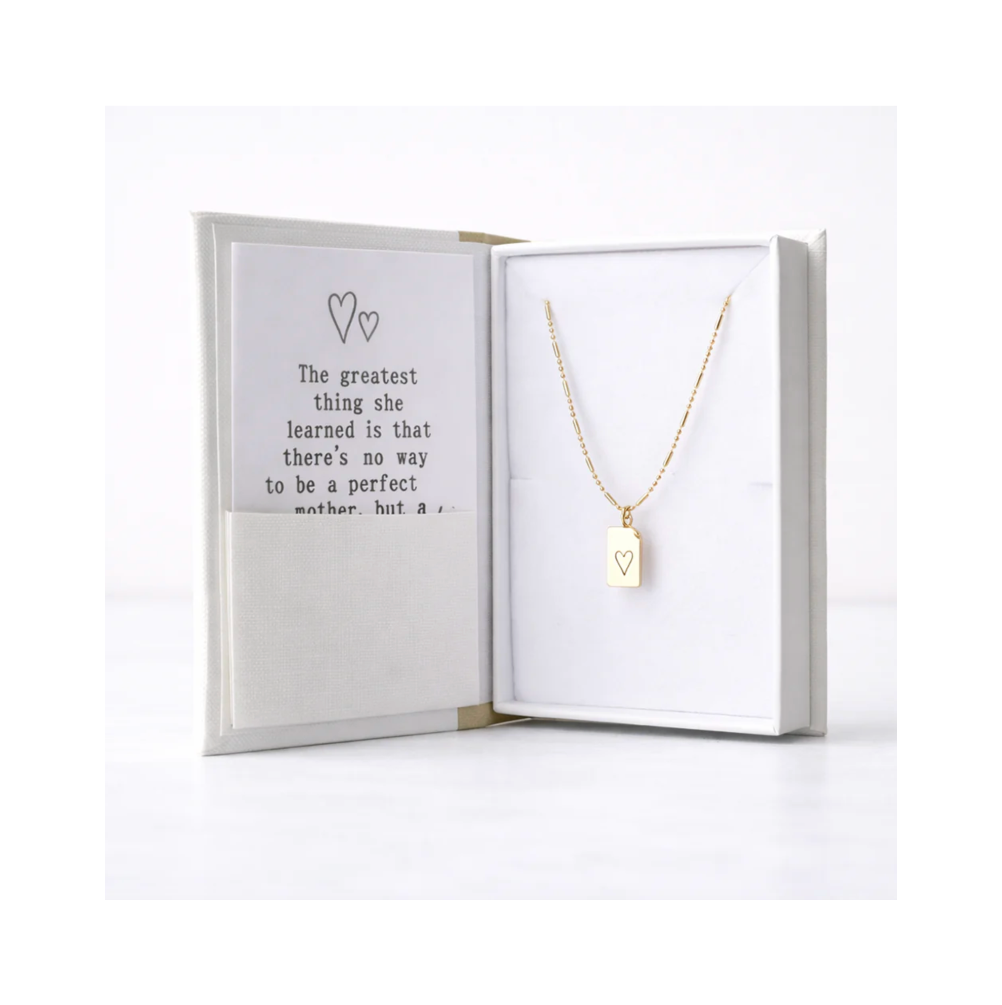 Gold necklace with a heart pendant in an open box with a message inside.