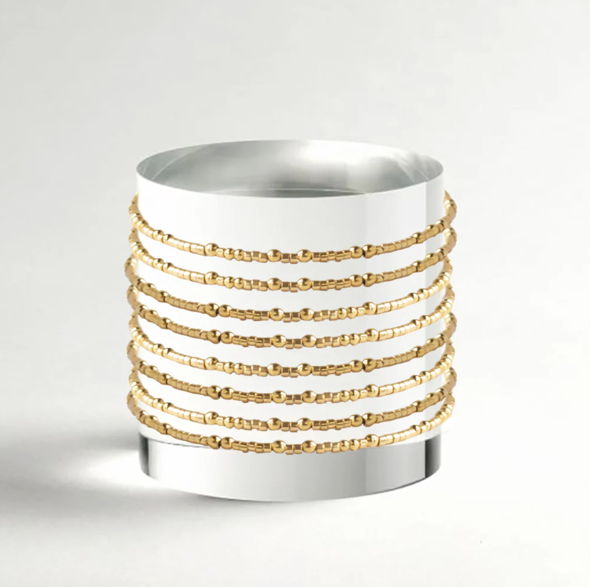 White candle holder with gold decorative bands on a light gray background