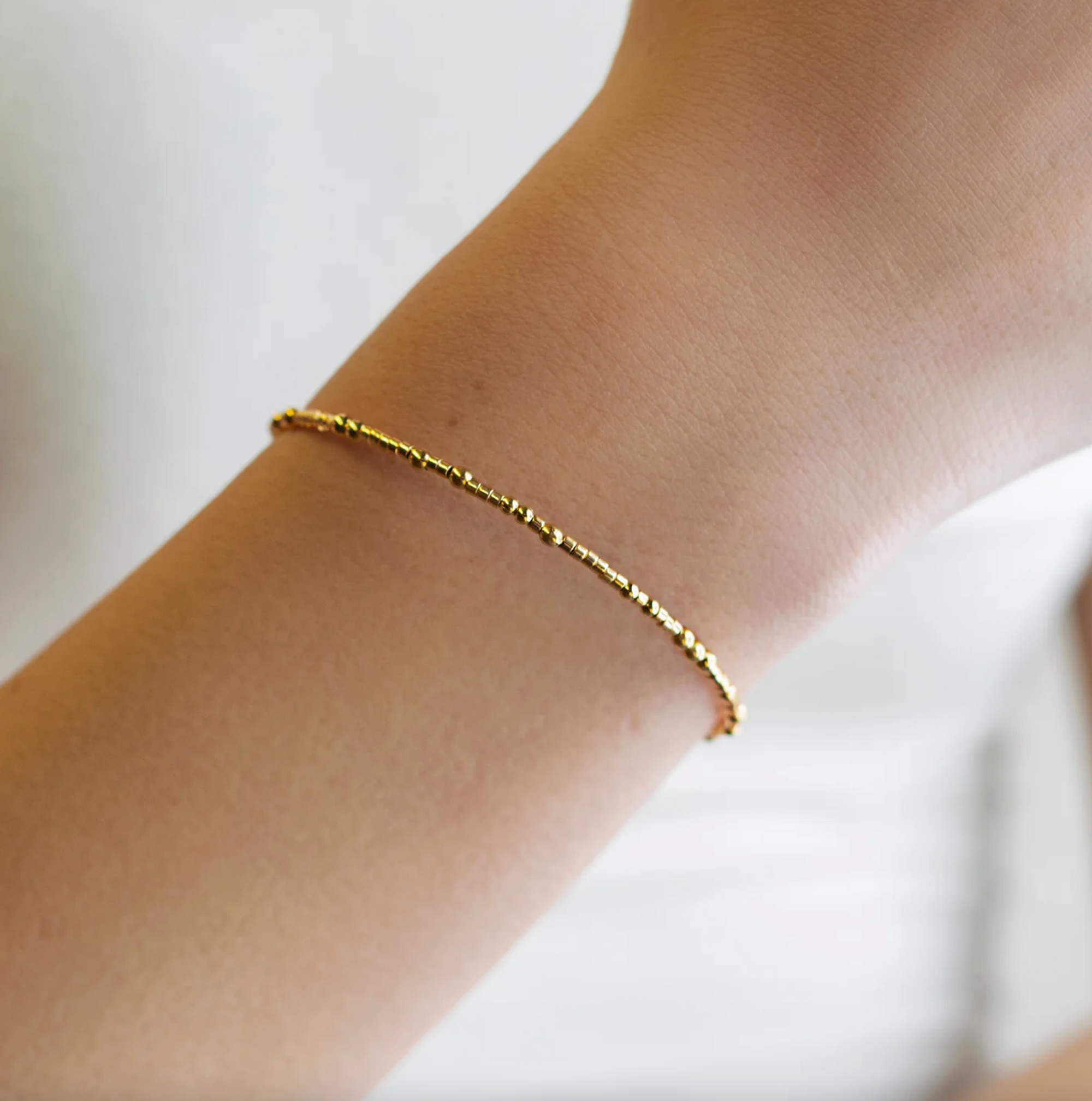 Gold bracelet on a person's wrist with a blurred background