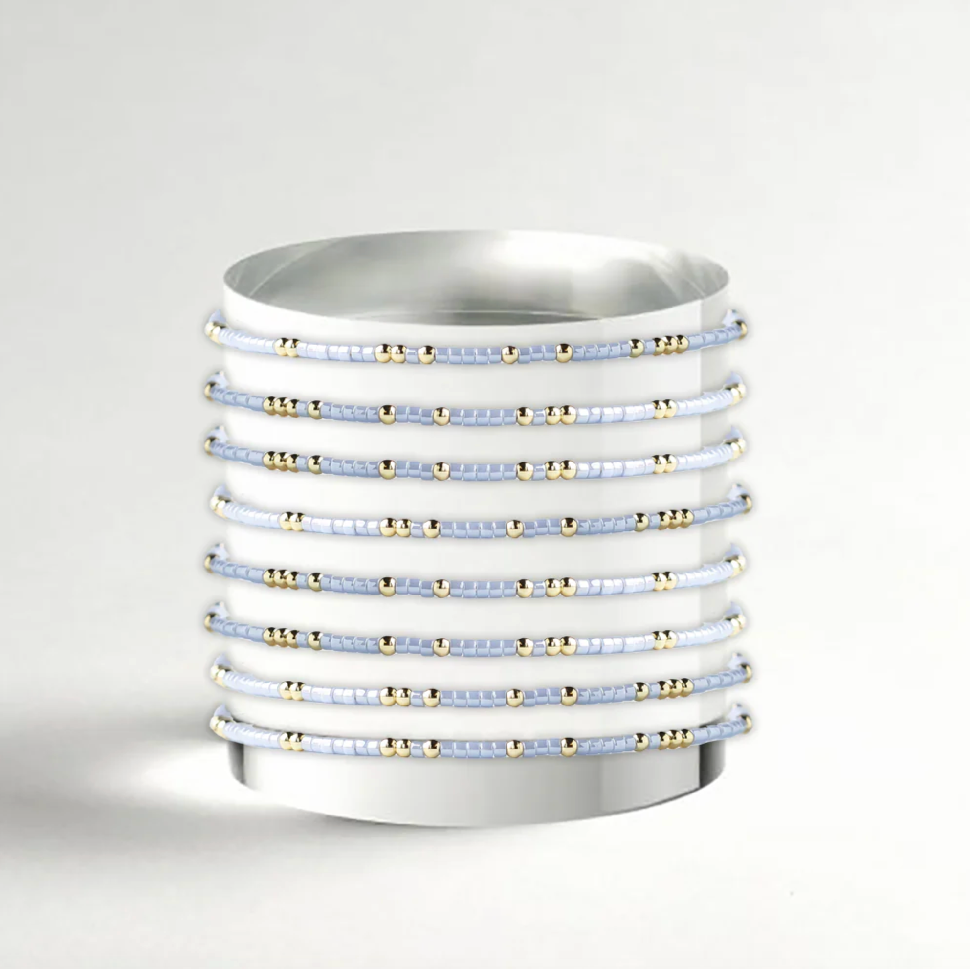 Stack of white bangles with gold accents on a light gray background