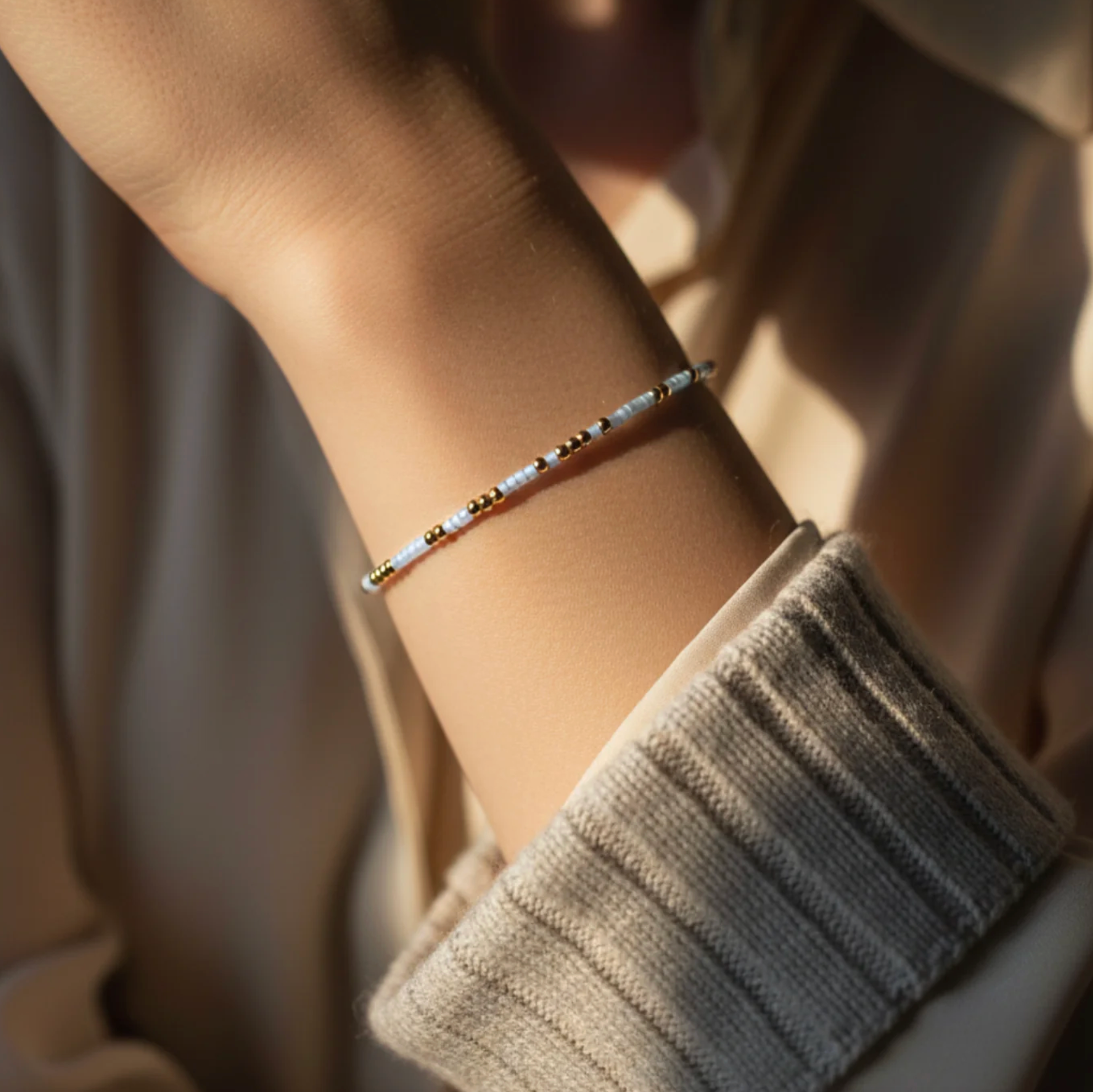 Close-up of a person's wrist wearing a delicate bracelet with a soft focus background.