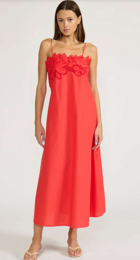 Woman wearing a red dress with floral details on a white background