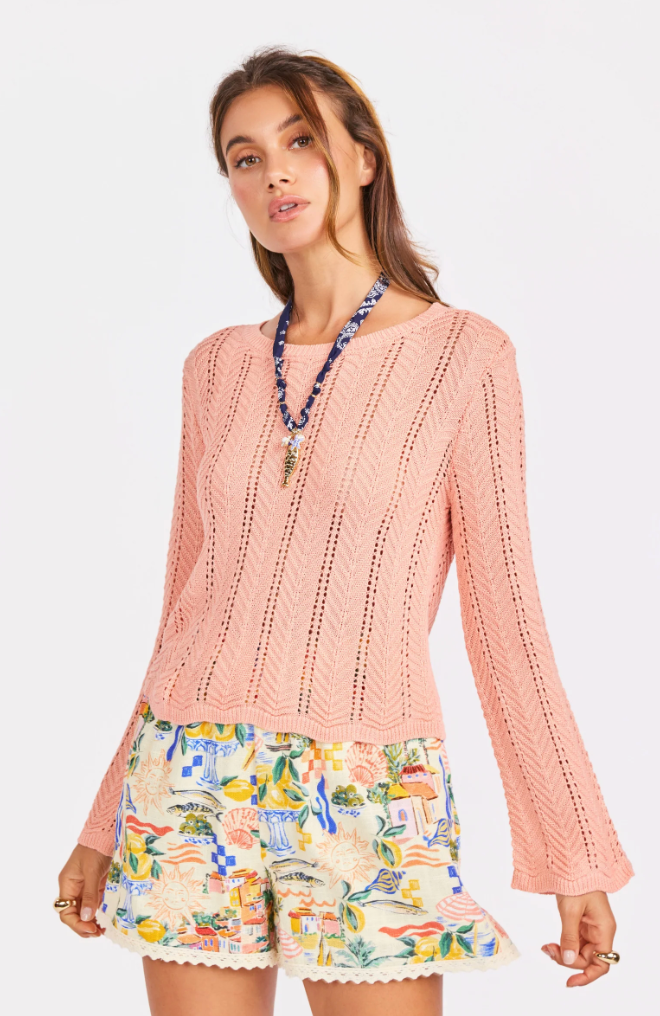 Woman wearing a pink knitted sweater and colorful shorts on a white background