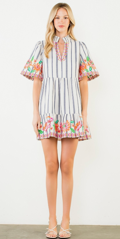 Woman wearing a striped dress with floral embroidery on a white background