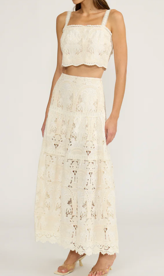 Woman wearing a white lace two-piece outfit on a plain background