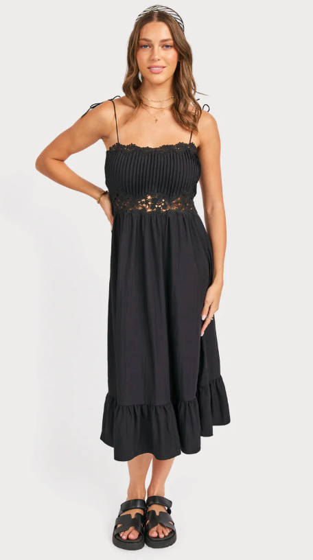 Woman wearing a black dress with floral embellishments on a white background