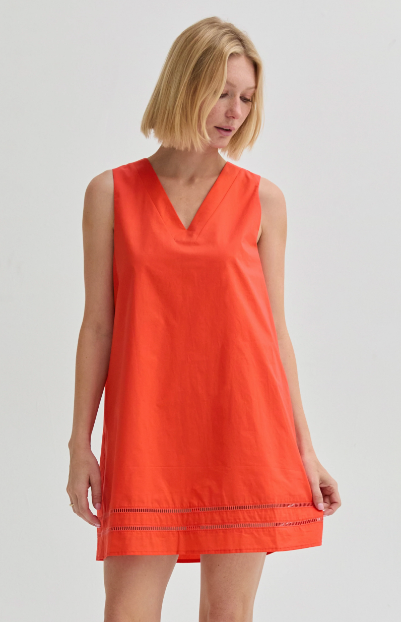Woman wearing an orange sleeveless dress on a plain background