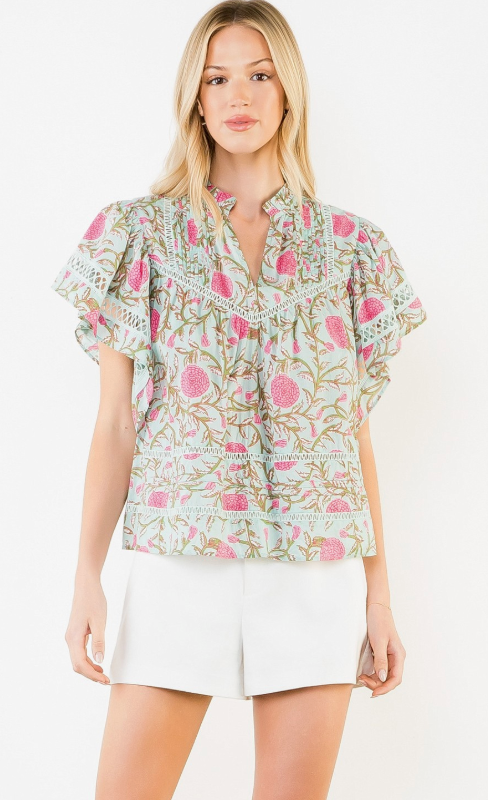 Woman wearing a floral blouse and white shorts on a white background