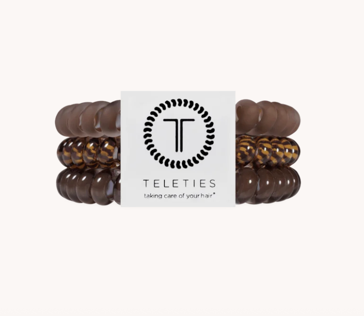 Three pairs of Teleties hair stretch bands in dark brown, glossy dark brown, and brown tortoiseshell patterns, arranged symmetrically on either side of a white brand label card.