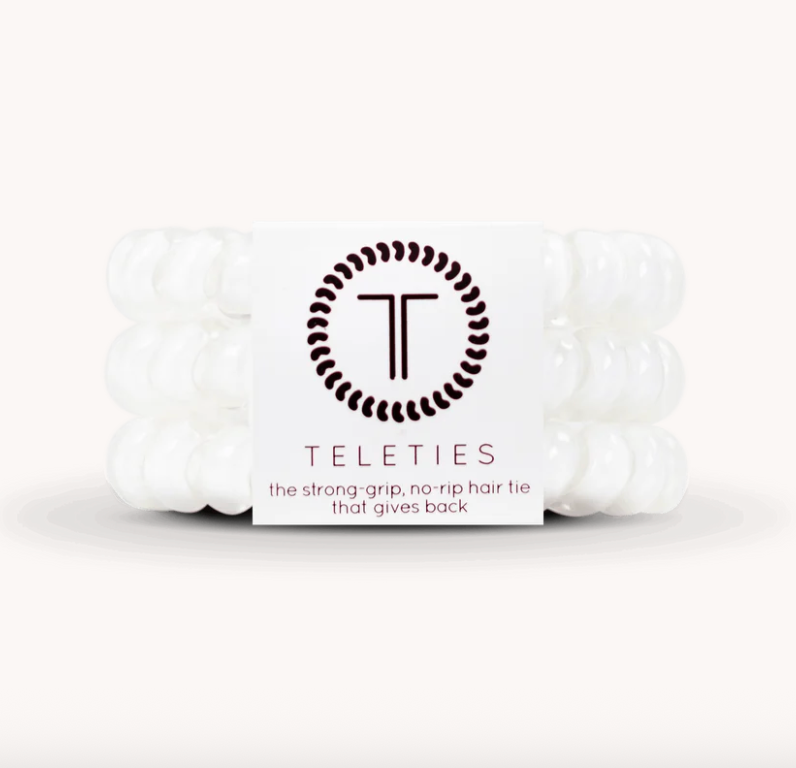 A pack of six white silicone hair ties wrapped together with a white paper band featuring the brand name 'TELETIES' and its logo, set against a plain white background.