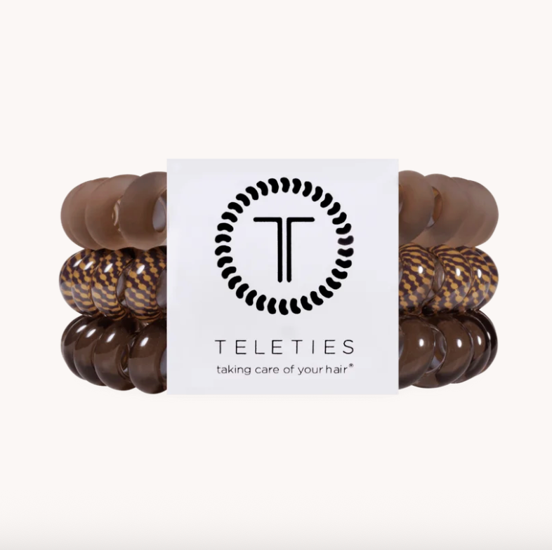 Four Teleties hair care bracelets arranged in two columns behind a white brand card. The set includes solid medium brown, glossy dark brown, and mottled brown-and-black leopard-print beads.