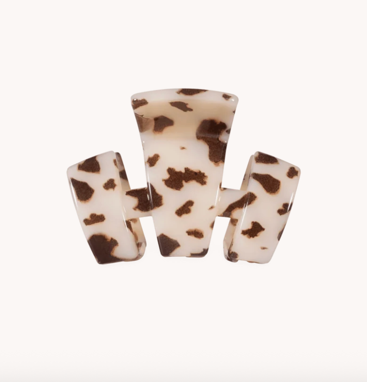 A three-prong  TELETIE hair claw clip made of glossy tortoiseshell-patterned resin, featuring a cream base with dark brown spots, set against a plain white background.
