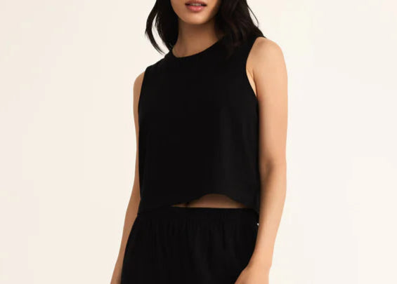 Person wearing a black sleeveless top and wide-leg pants on a beige background